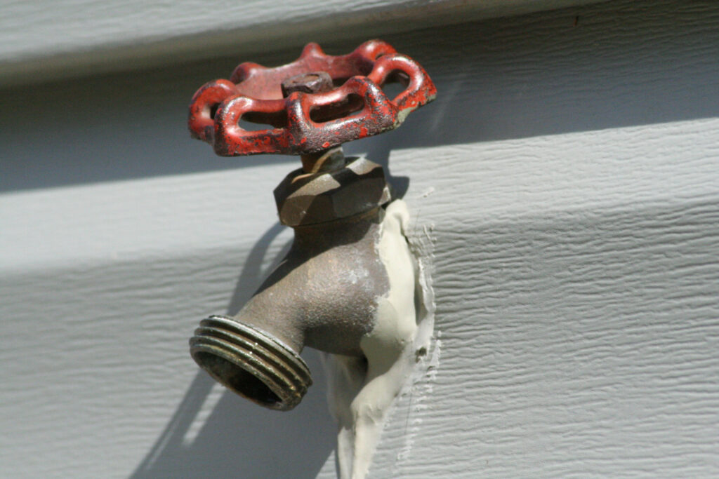 Outdoor hose bib faucet on house siding