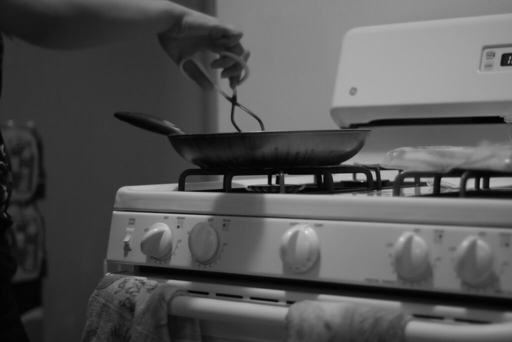 Person cooking with a frying pan on a gas stove