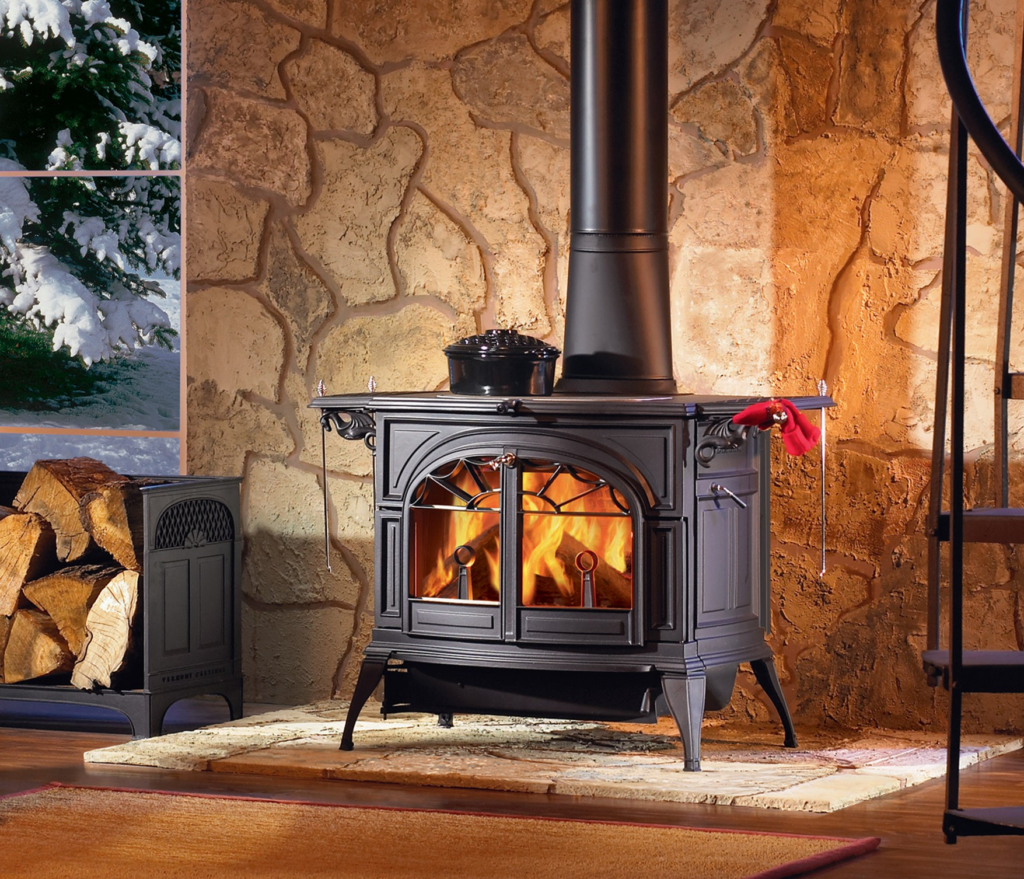 Cast iron wood stove burning in front of a stone wall