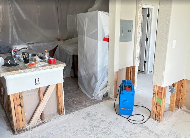 Rocky Mountain Catastrophe & Restoration crew mid-job: drywall cut, plastic containment and drying equipment in a Grand County kitchen