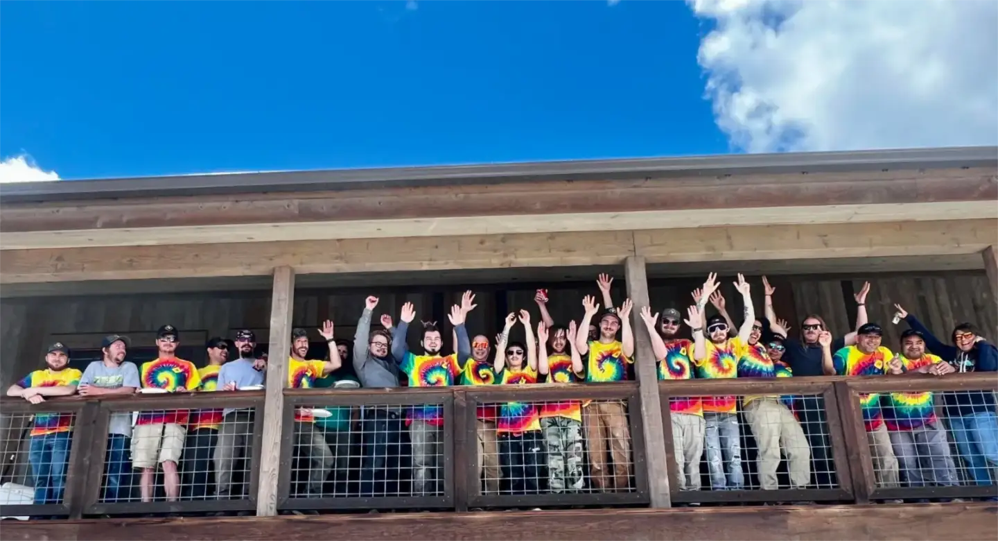 The Rocky Mountain Catastrophe & Restoration team in matching tie-dye shirts cheering on the office balcony