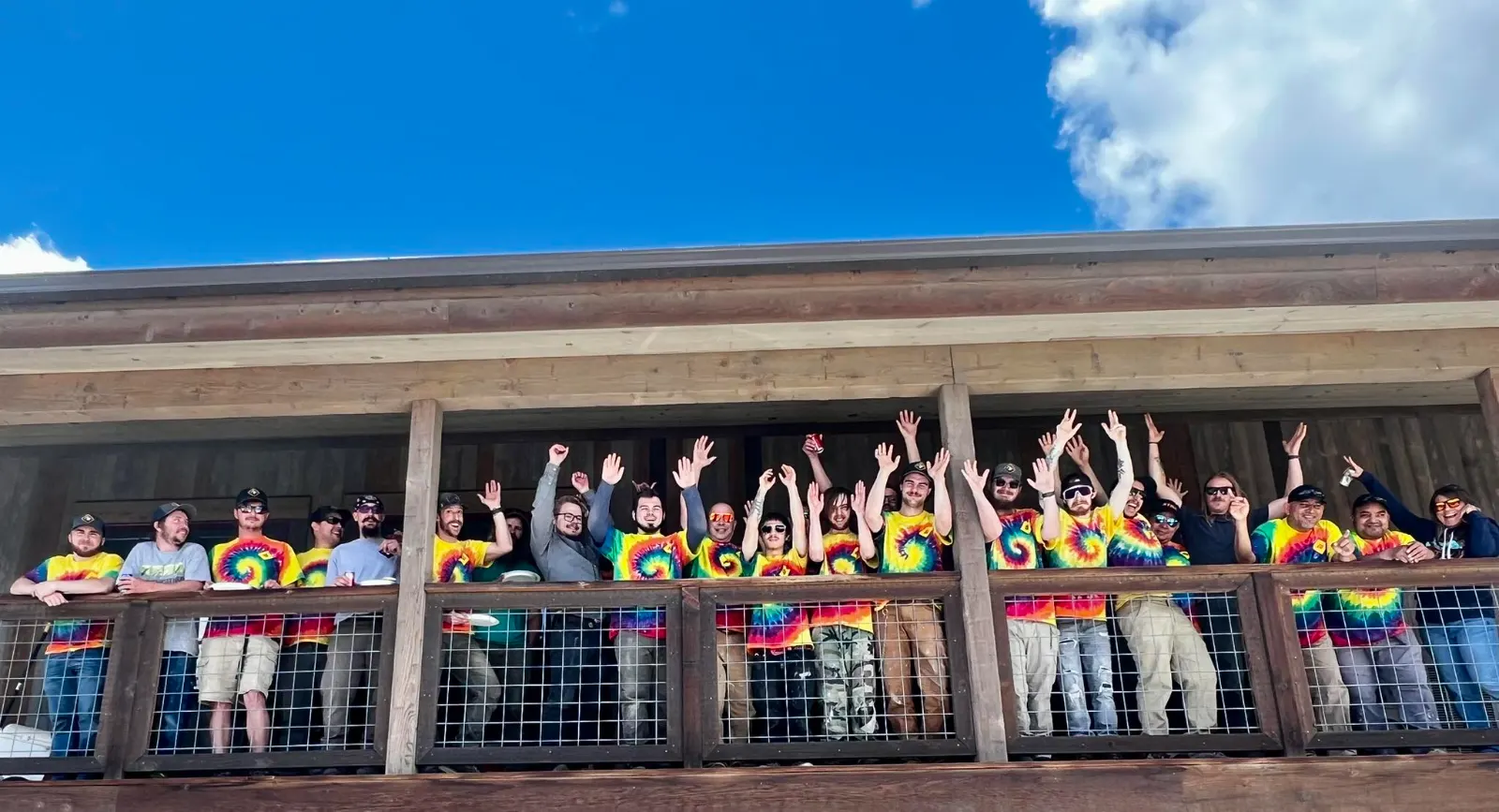 The Rocky Mountain Catastrophe & Restoration team in matching tie-dye shirts cheering on the office balcony